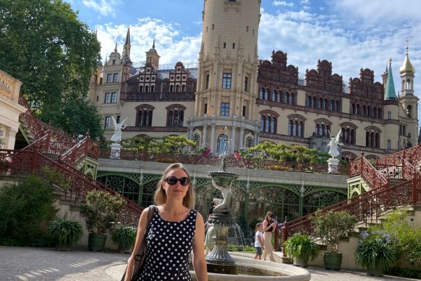 Frau mit Sonnenbrille vor einem historischen Gebäude